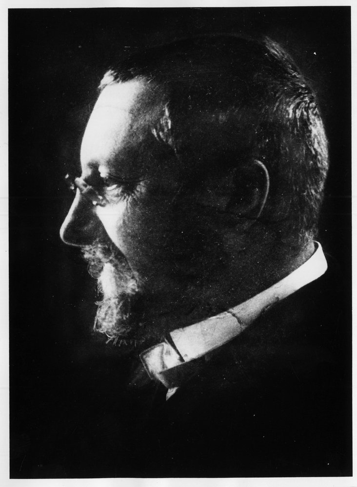 Black and white profile portrait of Alfred Binet against a dark background.