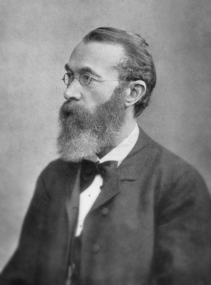 Side portrait of Alfred Binet in formal coat with bowtie, full beard and round glasses.