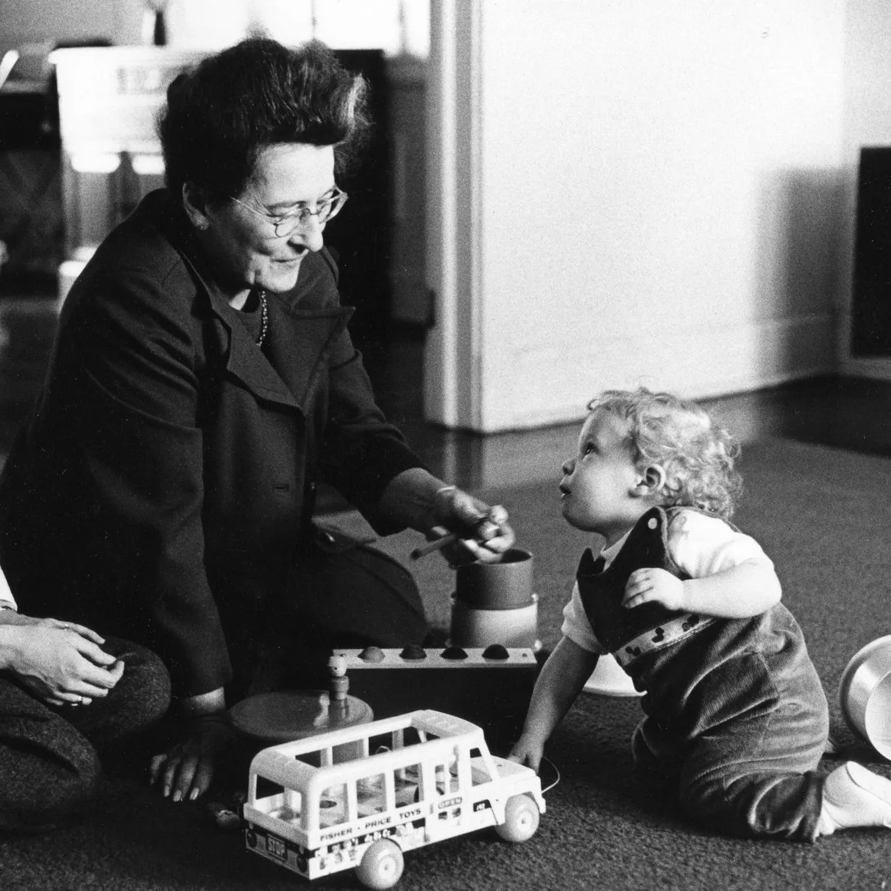 A child working through age-appropriate test materials including wooden blocks and a hammer-and-pegs toy.